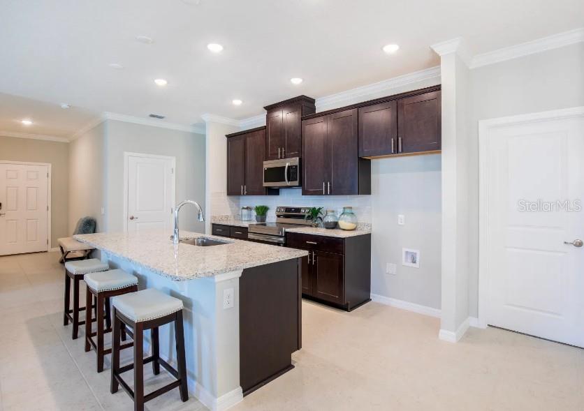 A kitchen features dark wood cabinets, granite countertops, a center island, and three bar stools — 17663 NW 169TH PLACE, ALACHUA, FL
