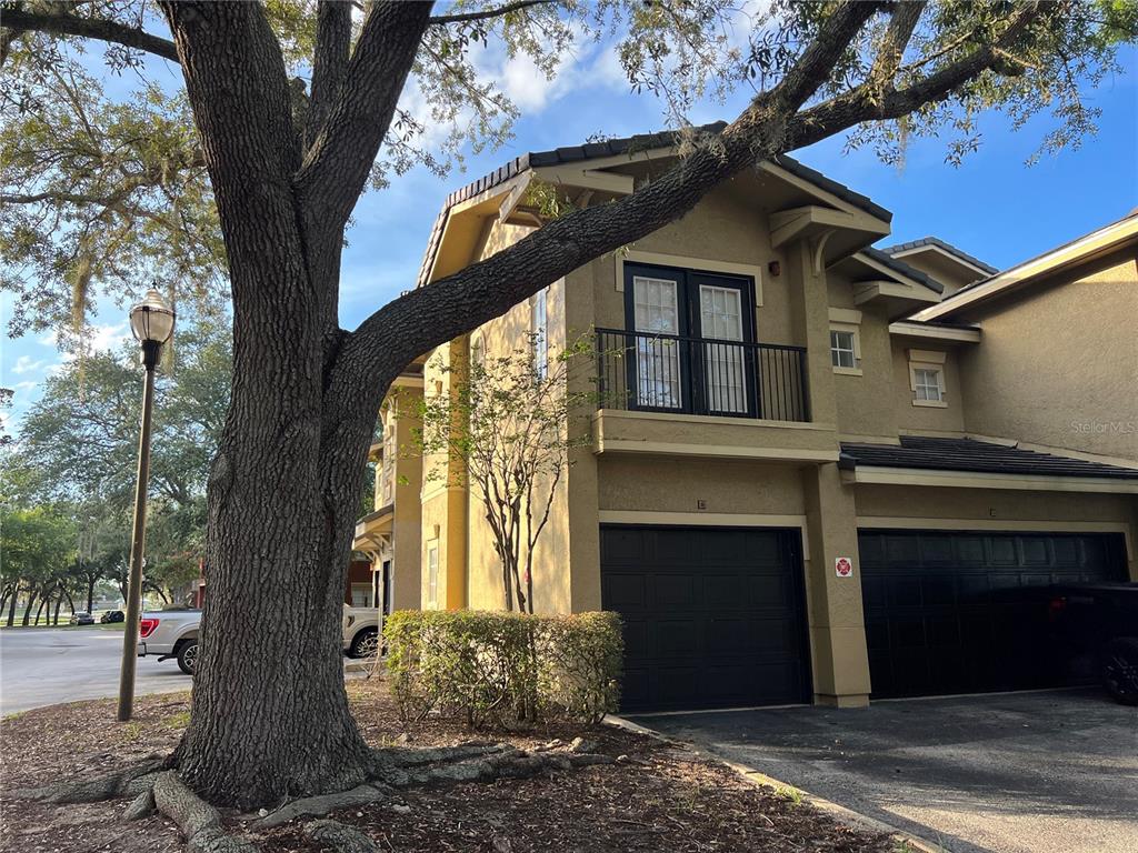 A two-story tan building with black garage doors and a second-floor balcony — 143 VILLA DI ESTE TERRACE UNIT 209, LAKE MARY, FL