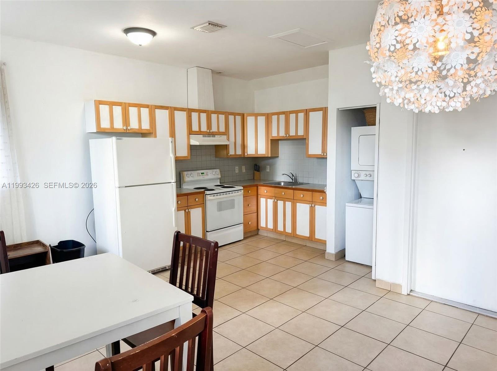 A kitchen features white and wood-toned cabinets, white appliances, and beige tile flooring — 404 NE 27th St, Miami FL 33137, MIAMI, FL