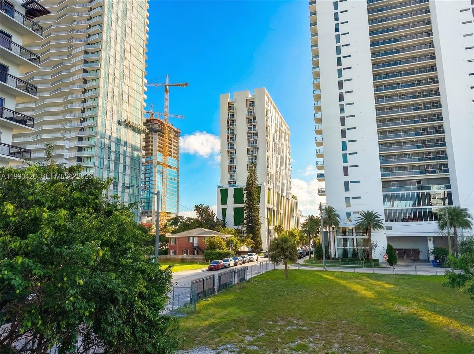 A view of three high-rise apartment buildings and a construction crane above a grassy lot — 404 NE 27th St, Miami FL 33137, MIAMI, FL