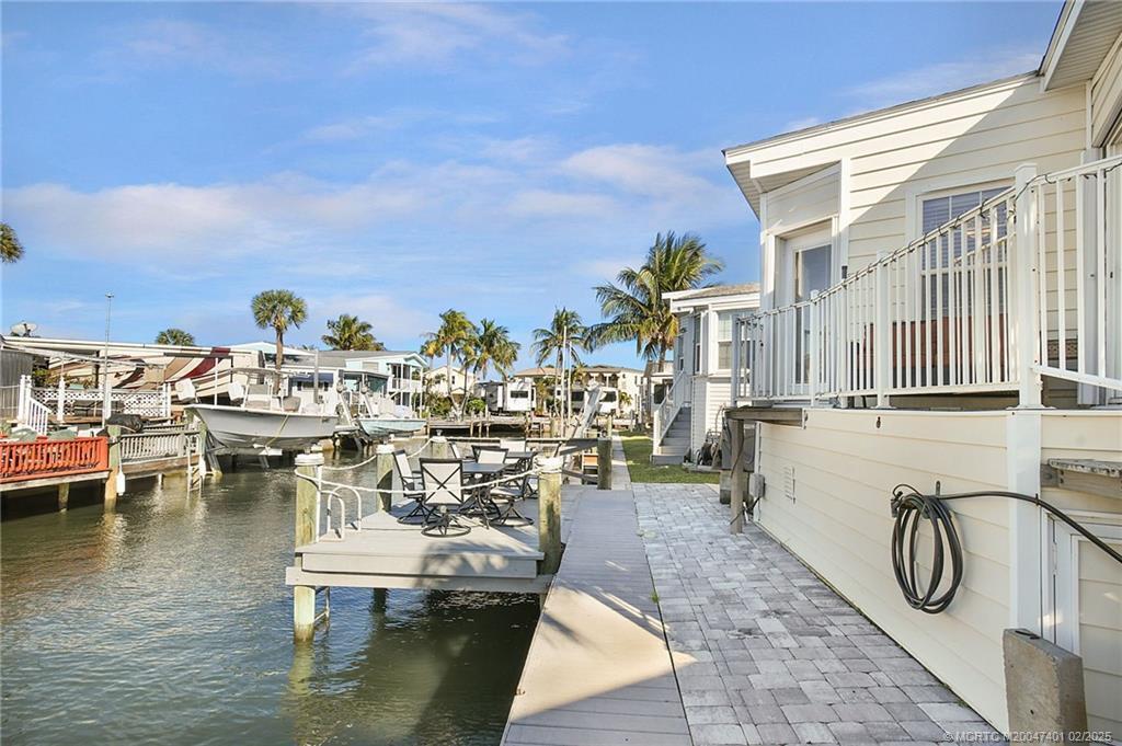 A waterfront home features a private dock with outdoor seating and a boat slip — 1092 Nettles Boulevard, Jensen Beach FL 34957, JENSEN BEACH, FL
