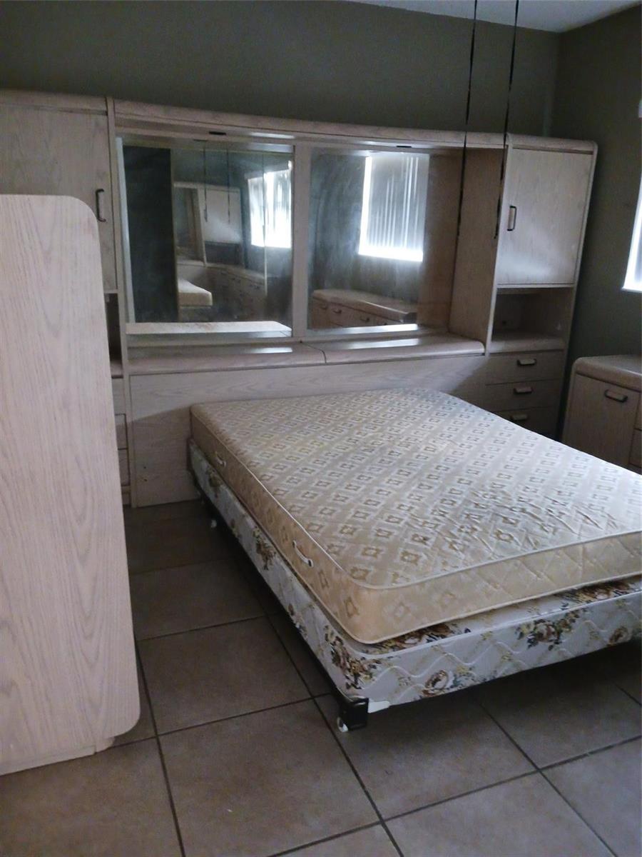 A bedroom features a light wood headboard unit with integrated mirrors, shelving, and storage drawers — 7605 W Atlantic Boulevard # 106, Margate FL 33063, MARGATE, FL