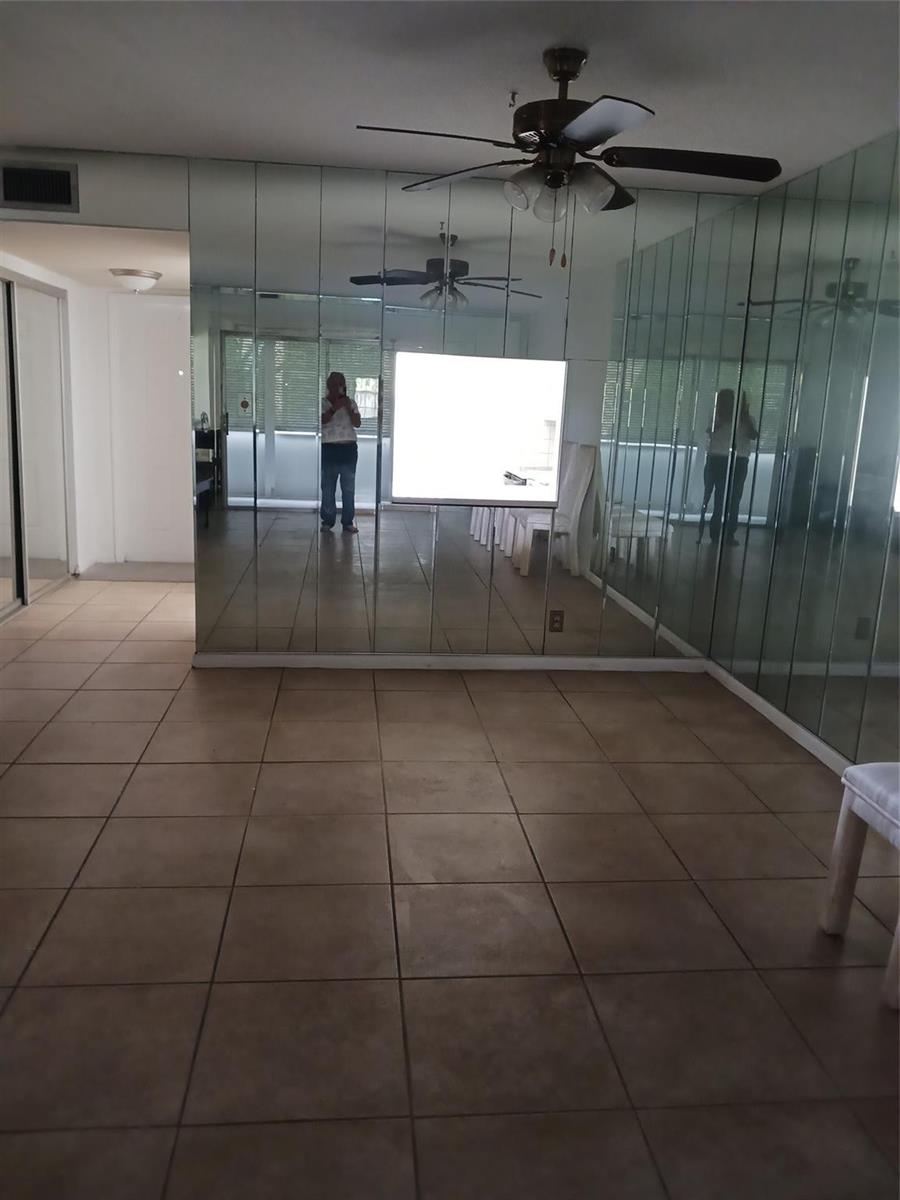 A room with tiled flooring and a wall covered in vertical mirror panels — 7605 W Atlantic Boulevard # 106, Margate FL 33063, MARGATE, FL