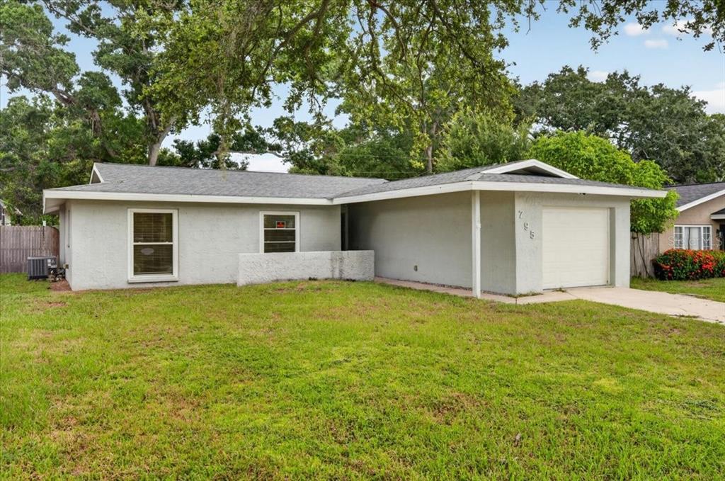 A single-story house with a garage, a concrete driveway, and a sunset sky background — 795 7TH STREET S, SAFETY HARBOR, FL