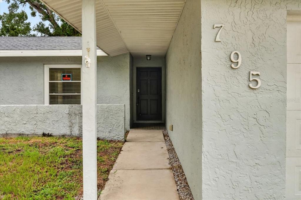 A single-story house with a gray stucco exterior, a one-car garage, and a grassy yard — 795 7TH STREET S, SAFETY HARBOR, FL