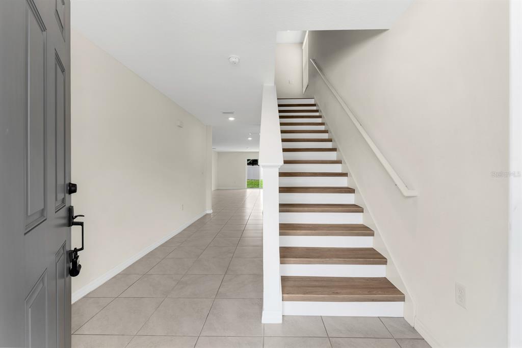 An entryway features light-colored tile flooring, a staircase with wood treads, and a gray door — 12153 DOWNY BIRCH DRIVE, RIVERVIEW, FL