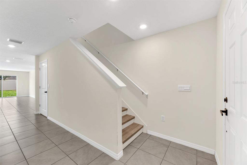 A tiled entryway features a staircase with wood-look treads and a white handrail — 12153 DOWNY BIRCH DRIVE, RIVERVIEW, FL