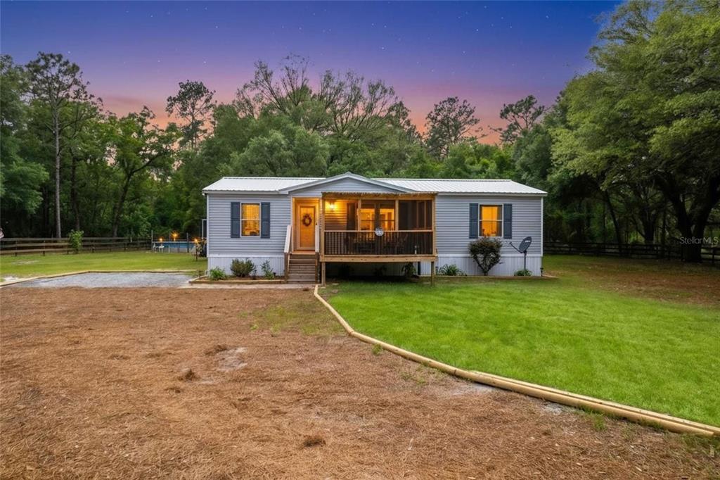 A single-story manufactured home with a screened front porch sits on a grassy lot — 7360 SW 157TH LANE, DUNNELLON, FL