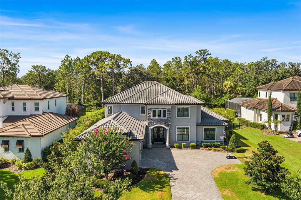 An aerial view of a two-story suburban house with a stone facade and paved driveway — 14704 FISHHAWK PRESERVE DRIVE, LITHIA, FL