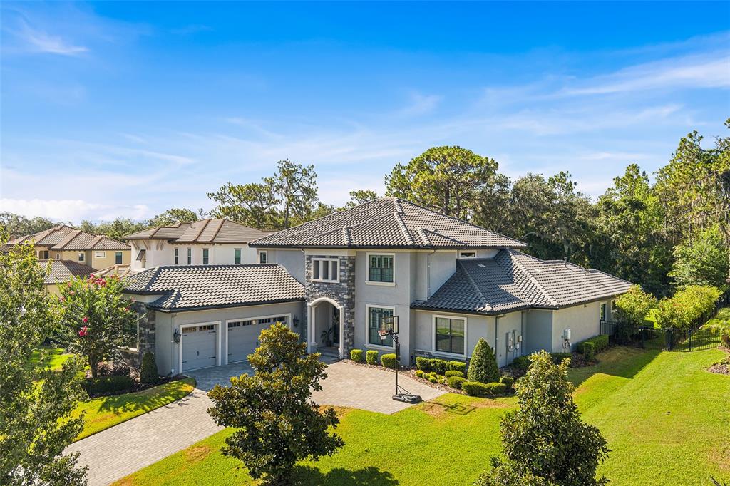 A two-story suburban house with a tile roof, stone accents, and a paved driveway — 14704 FISHHAWK PRESERVE DRIVE, LITHIA, FL