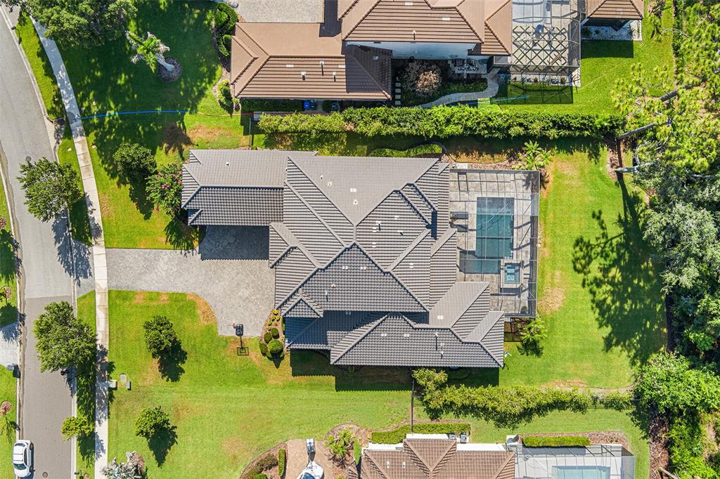 An aerial view shows a house with a gray tiled roof, pool enclosure, and driveway — 14704 FISHHAWK PRESERVE DRIVE, LITHIA, FL