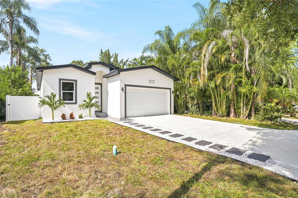 A white single-story house with a garage and a paved driveway sits on a lawn — 1117 15TH AVENUE NW, LARGO, FL