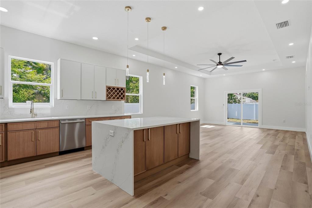 A modern kitchen features wood cabinets, a white quartz island, and light wood flooring — 1117 15TH AVENUE NW, LARGO, FL