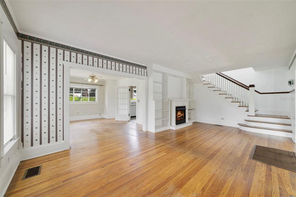A living room with hardwood floors, a fireplace, built-in shelves, and a staircase — 530 N RIDGE AVENUE, LAKE ALFRED, FL