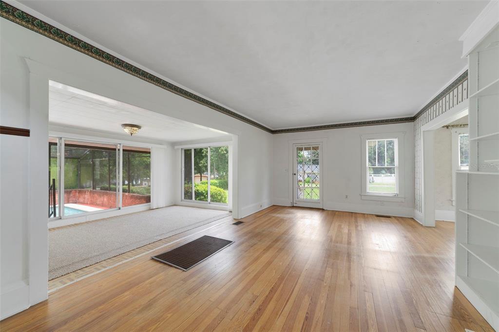 A living room with hardwood floors, a carpeted sunroom, and a view of a pool — 530 N RIDGE AVENUE, LAKE ALFRED, FL