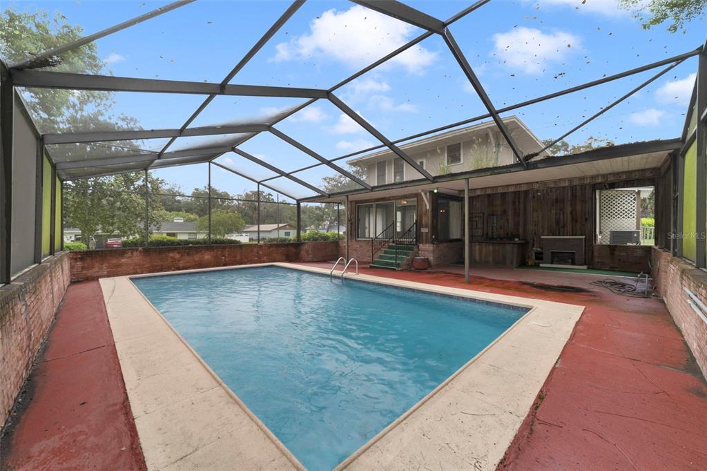 A rectangular swimming pool sits inside a screened-in enclosure with a red concrete deck — 530 N RIDGE AVENUE, LAKE ALFRED, FL