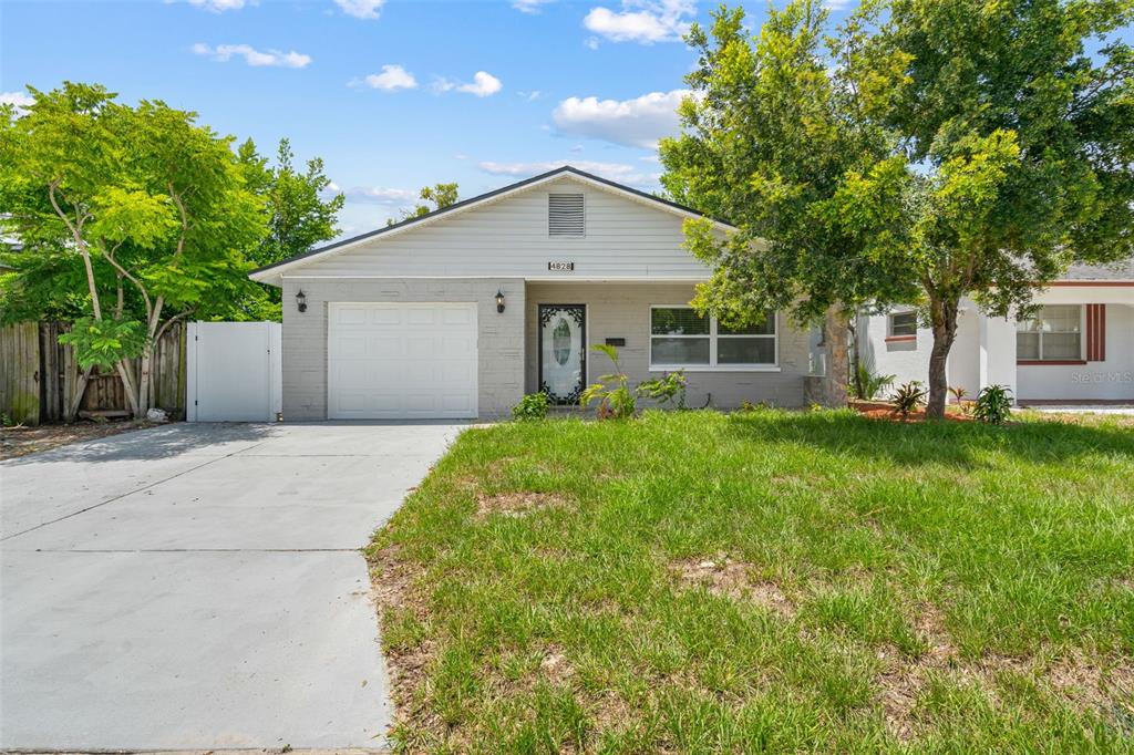 A single-story house with a gray brick facade, a white garage door, and a front lawn — 4828 22ND AVENUE N, ST PETERSBURG, FL