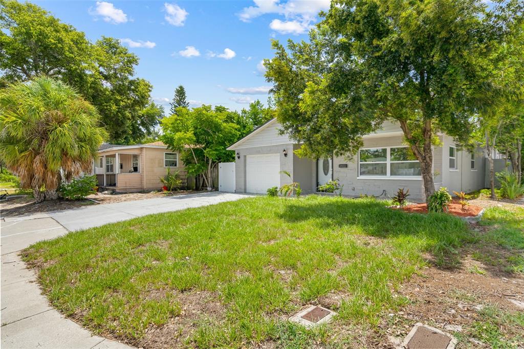 A single-story house with a white garage and gray siding sits behind a grassy lawn — 4828 22ND AVENUE N, ST PETERSBURG, FL