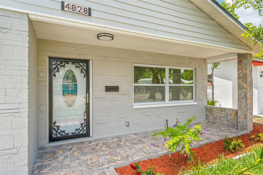 The exterior of a house features a stone-tiled porch, a glass-paneled front door, and siding — 4828 22ND AVENUE N, ST PETERSBURG, FL