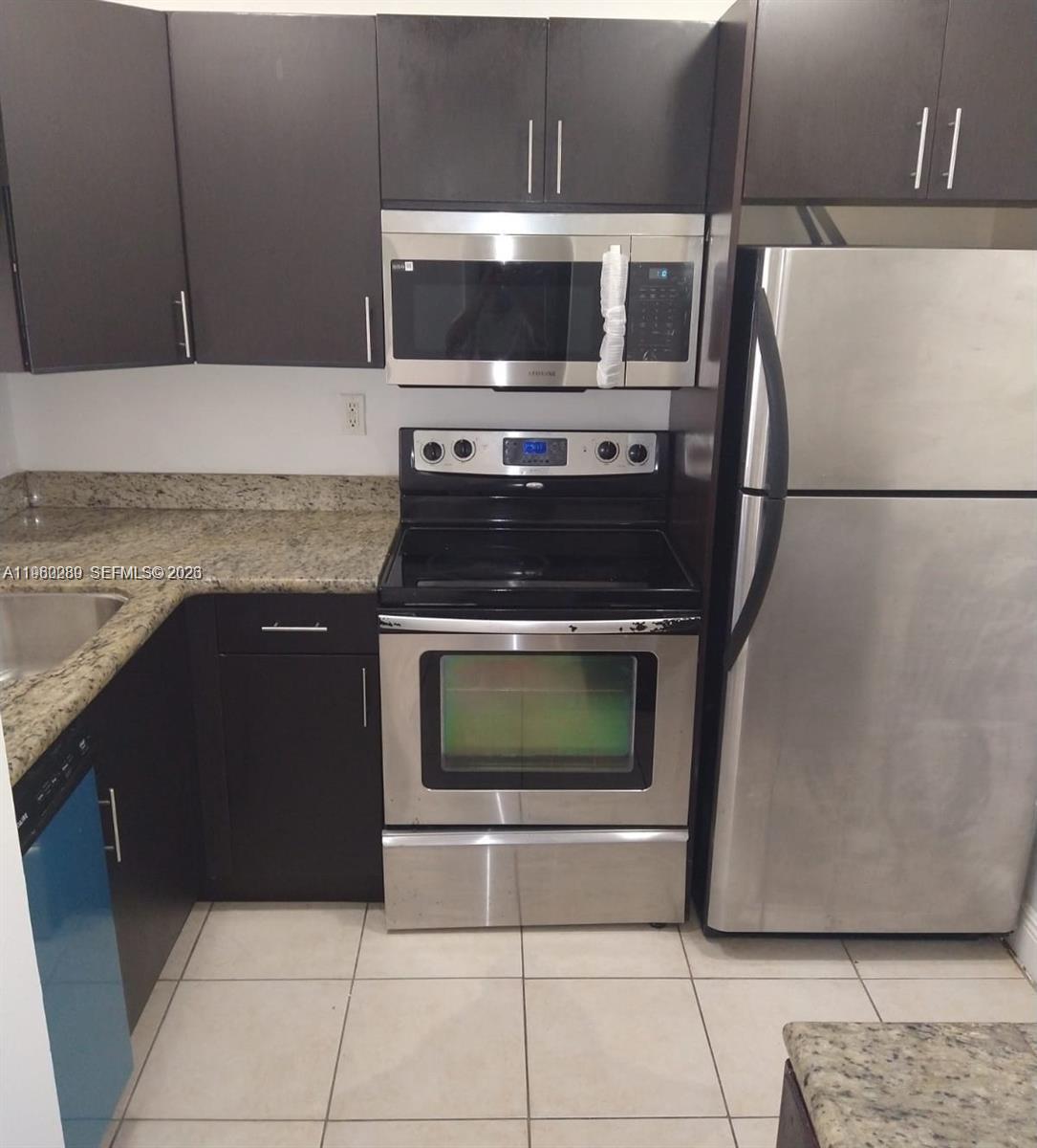 A kitchen features dark cabinets, granite countertops, and stainless steel appliances — 488 NW 165 St Rd # 310, Miami FL 33169, MIAMI, FL