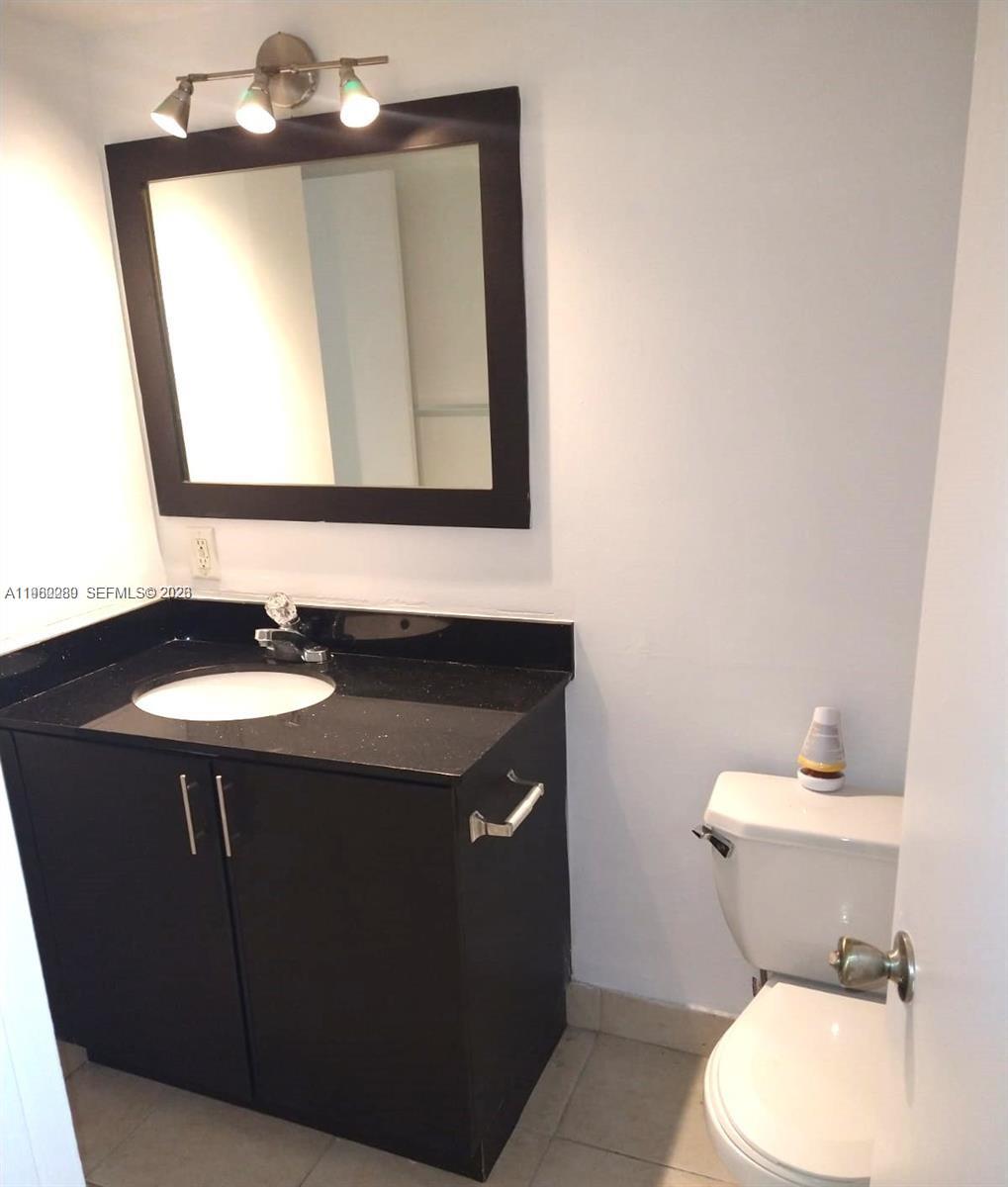 A bathroom features a black vanity with a white sink, a mirror, and a toilet — 488 NW 165 St Rd # 310, Miami FL 33169, MIAMI, FL