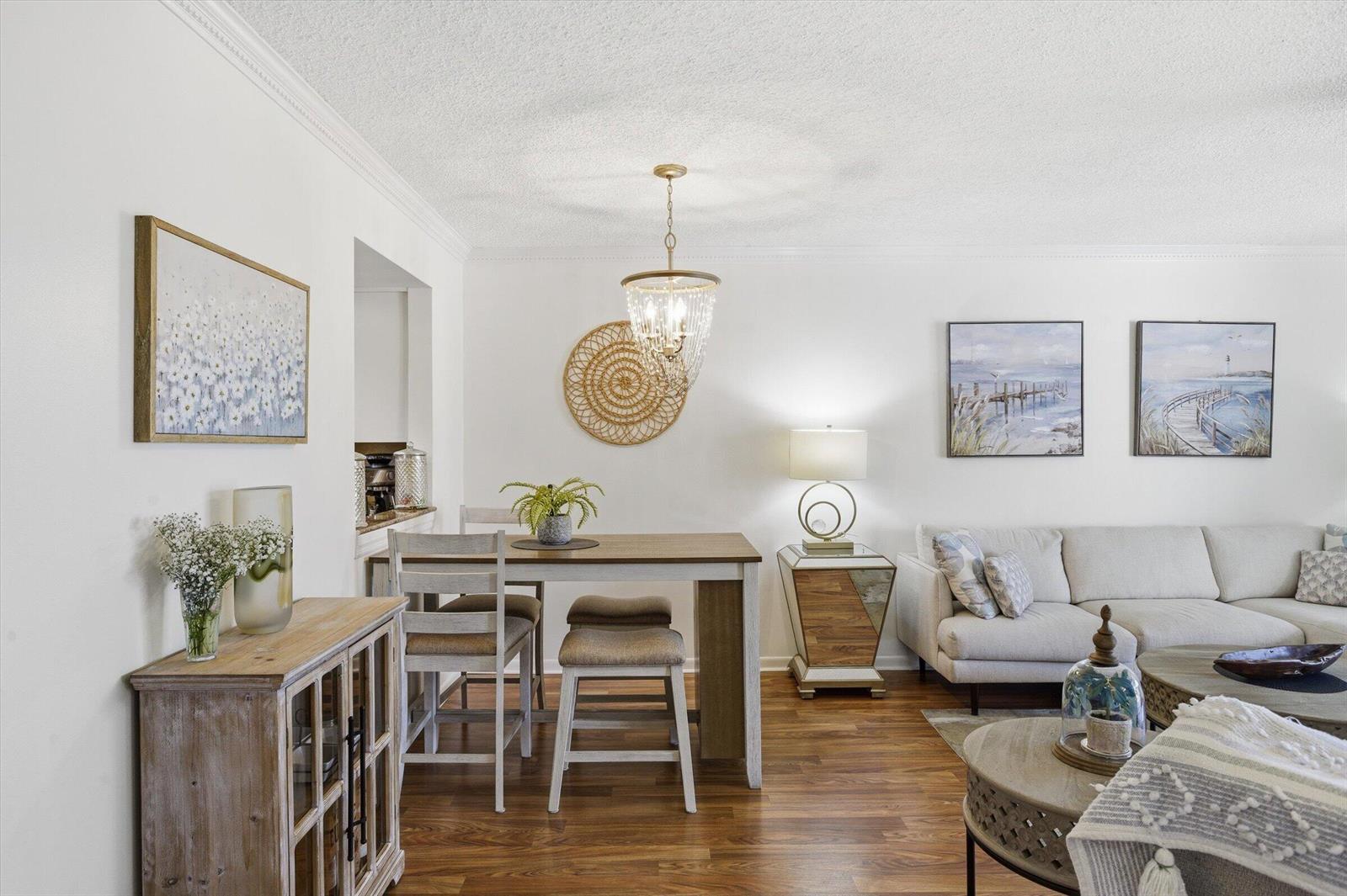 A dining area with a wooden table and chairs sits adjacent to a living room — 5370 Las Verdes Circle # 303, Delray Beach FL 33484, DELRAY BEACH, FL