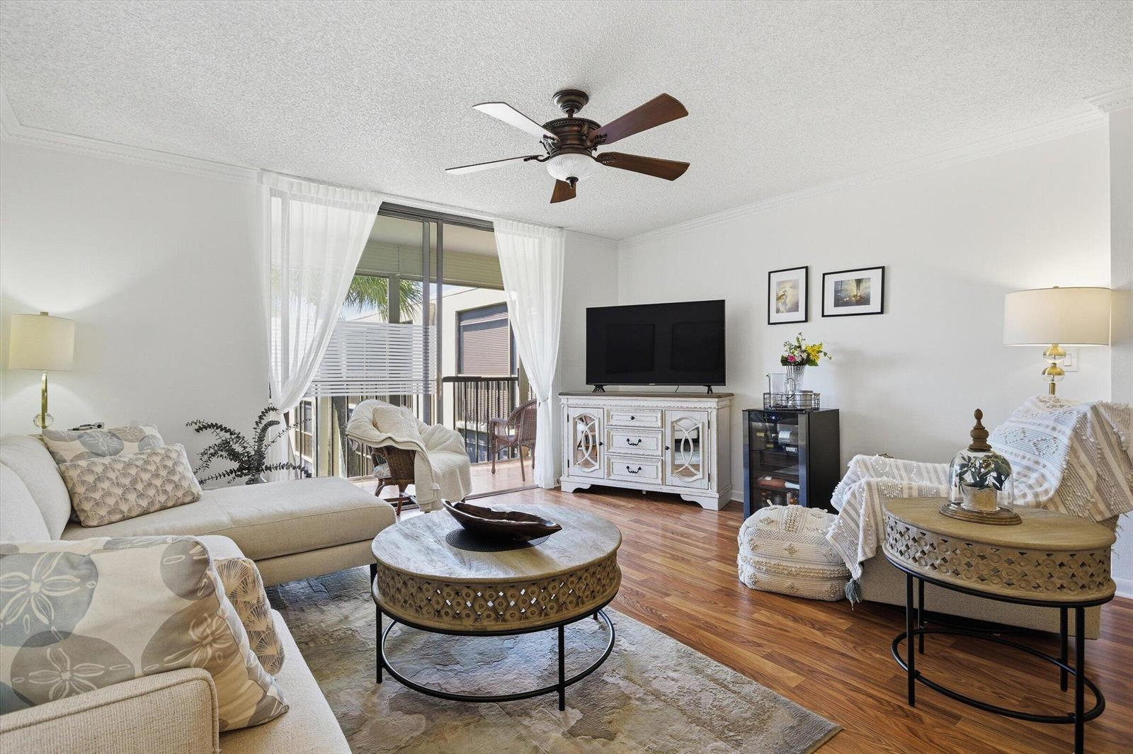 A living room features a sectional sofa, round coffee table, media console, and sliding glass doors — 5370 Las Verdes Circle # 303, Delray Beach FL 33484, DELRAY BEACH, FL