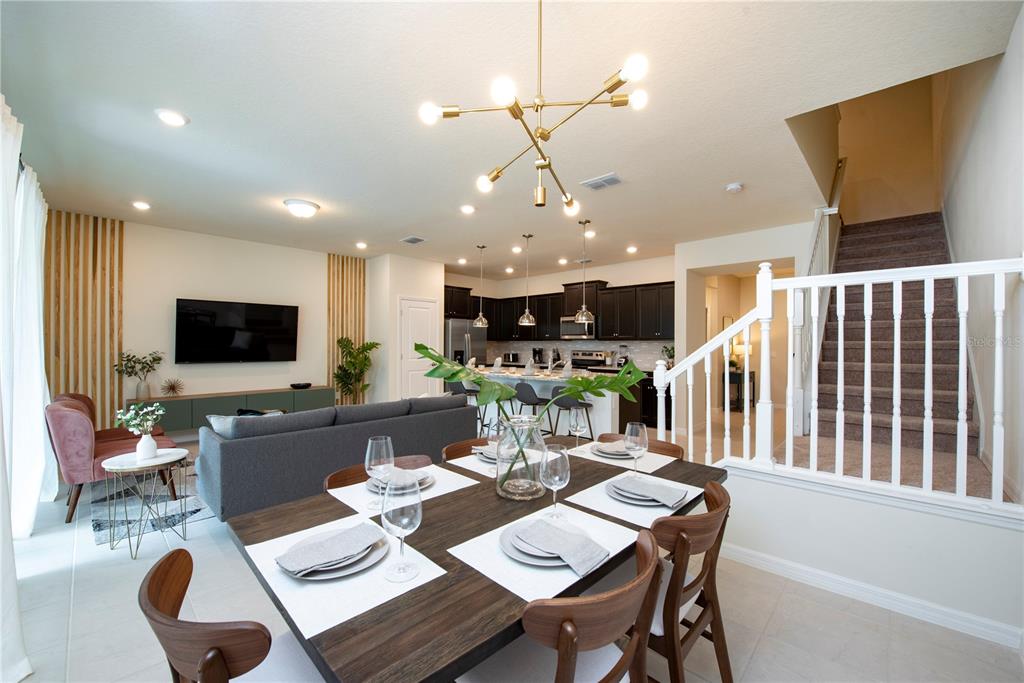An open-concept living and dining area features a modern kitchen, dark cabinetry, and a staircase — 126 JETTY WAY, DAVENPORT, FL
