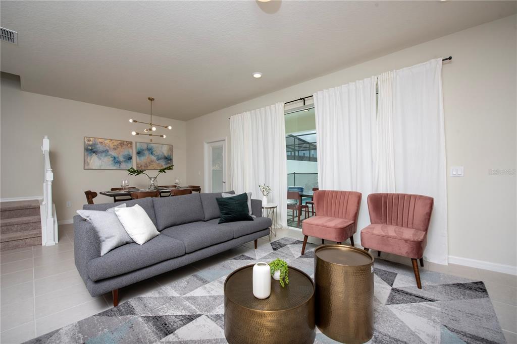 A living room features a grey sofa, two pink chairs, and a dining area — 126 JETTY WAY, DAVENPORT, FL
