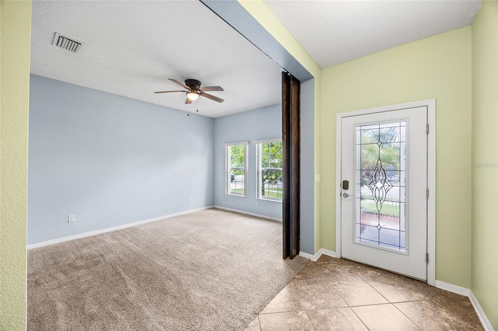 An entryway with tile flooring leads into a carpeted living area with a ceiling fan — 3851 PACENTE LOOP, WESLEY CHAPEL, FL
