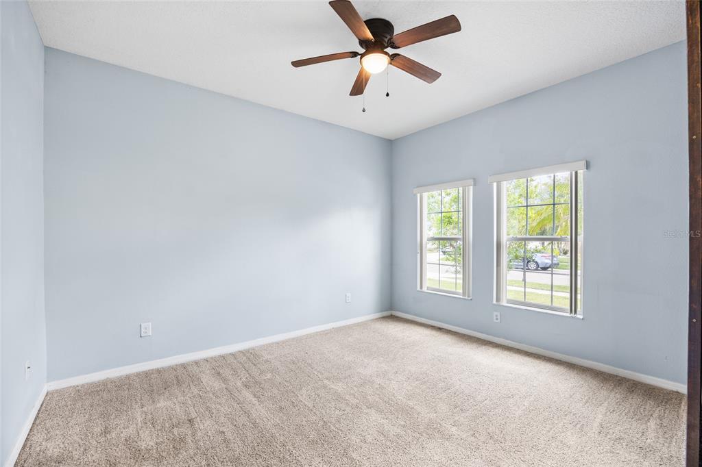 An empty bedroom with light blue walls, beige carpet, and a ceiling fan — 3851 PACENTE LOOP, WESLEY CHAPEL, FL