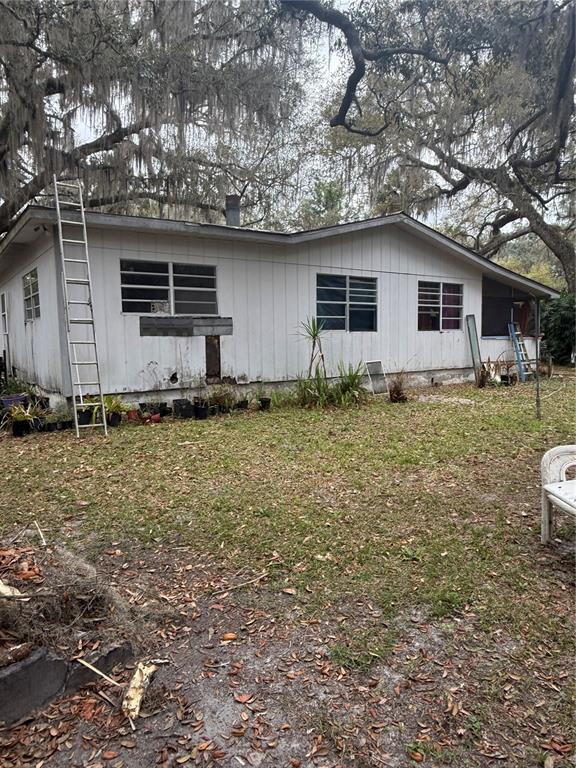 The exterior of a single-story house with white vertical siding and a metal ladder — 1730 S PALM AVENUE, HOMOSASSA, FL