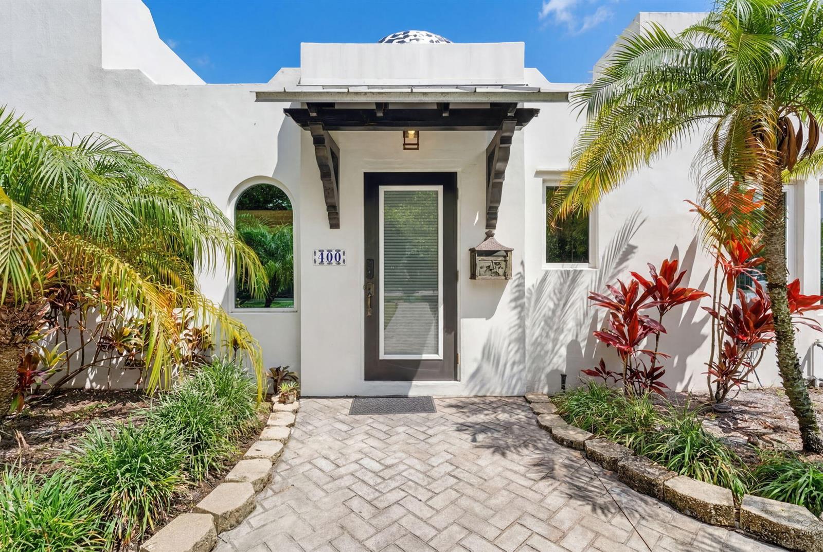 A white stucco house entrance features a dark wood awning, glass door, and brick walkway — 400 NE 5th Avenue, Pompano Beach FL 33060, POMPANO BEACH, FL