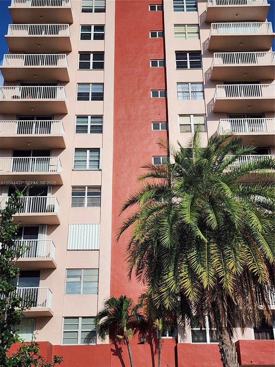A low-angle view of a multi-story apartment building with balconies and a large palm tree — 3161 S Ocean Dr # 301, Hallandale Beach FL 33009, HALLANDALE BEACH, FL