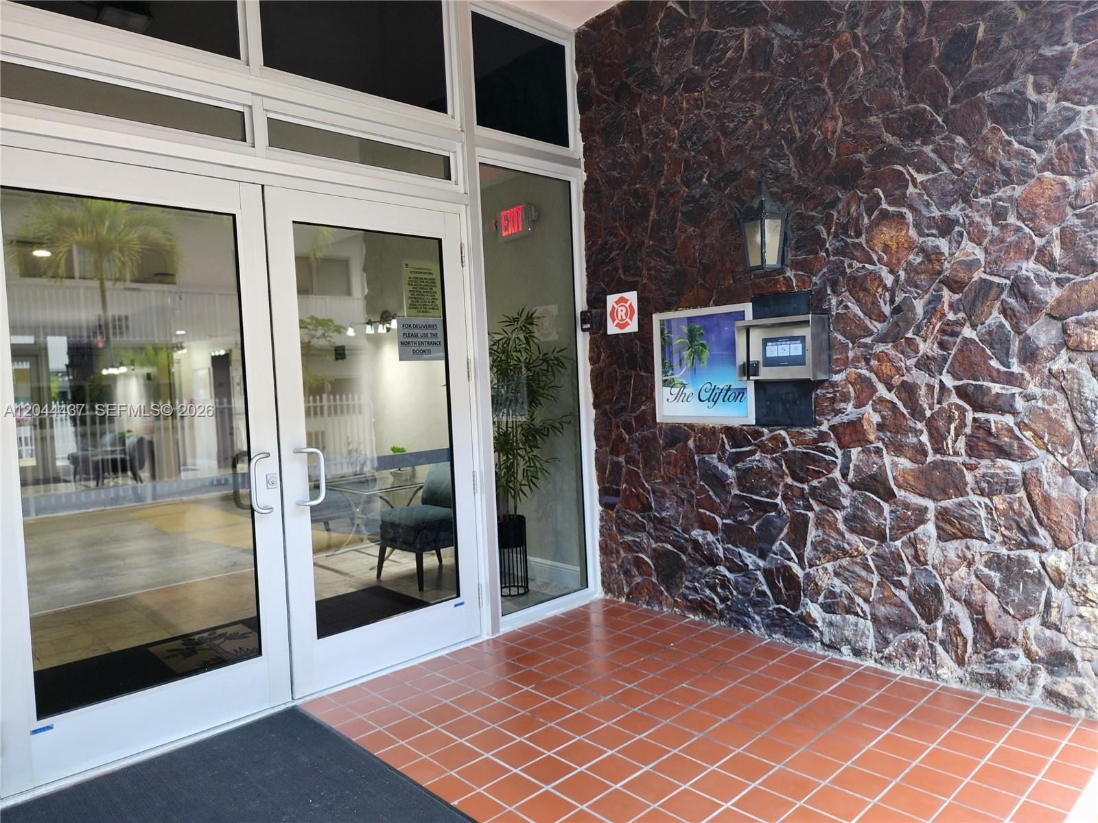 The entrance to The Clifton features glass doors, a stone wall, and a digital intercom — 3161 S Ocean Dr # 301, Hallandale Beach FL 33009, HALLANDALE BEACH, FL