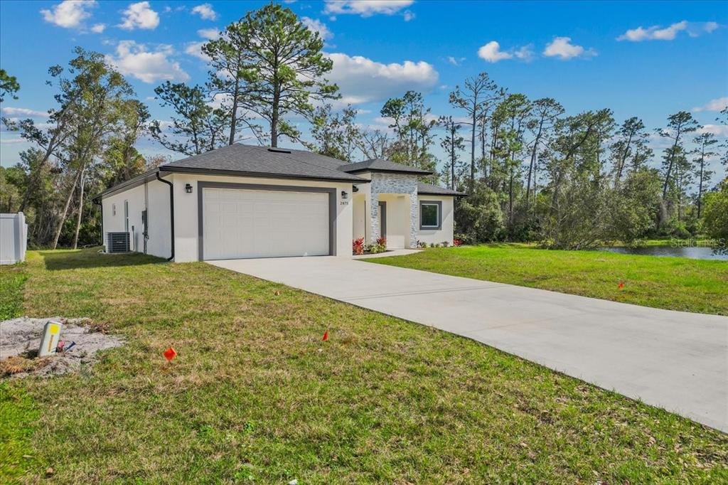 A single-story house with a white exterior, a two-car garage, and a stone-accented entryway — 2875 E SLATER DRIVE, DELTONA, FL
