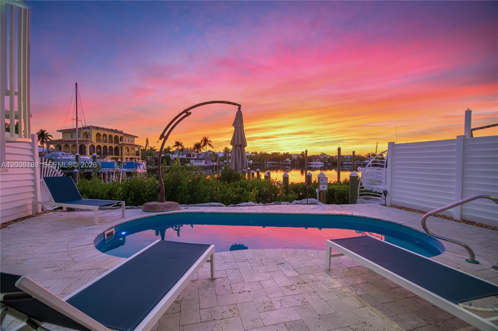 A small pool sits on a stone patio overlooking a canal at sunset — 443 Sombrero Beach Rd, Marathon FL 33050, MARATHON, FL