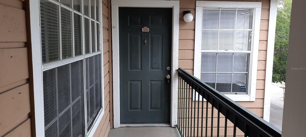 An exterior view of an apartment entrance with a dark door and a metal railing — 4200 THORNBRIAR LANE UNIT E-306, ORLANDO, FL