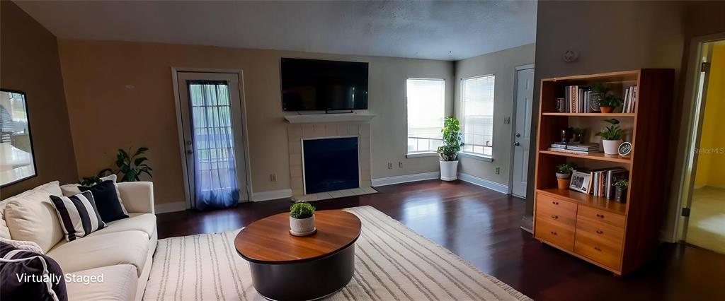 A living room features hardwood floors, a fireplace with a mounted television, and a bookshelf — 4200 THORNBRIAR LANE UNIT E-306, ORLANDO, FL