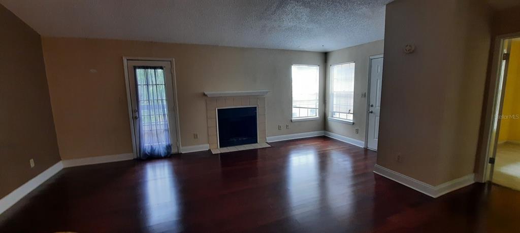 A living room features dark hardwood floors, a fireplace with a mantel, and two windows — 4200 THORNBRIAR LANE UNIT E-306, ORLANDO, FL