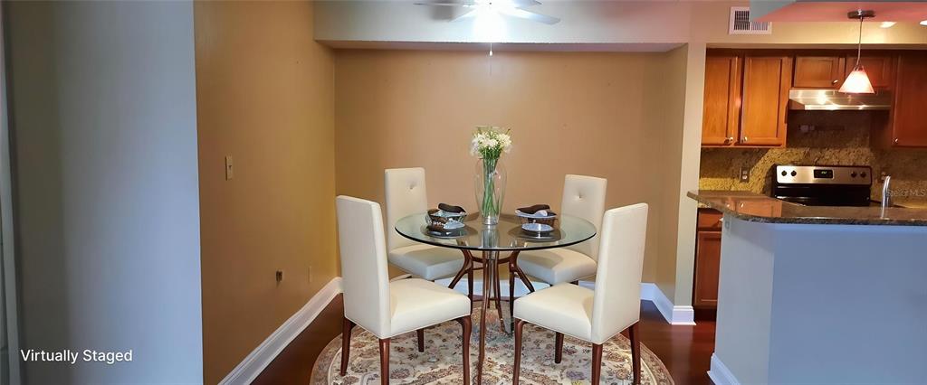 A dining area with a glass table and four chairs adjacent to a kitchen — 4200 THORNBRIAR LANE UNIT E-306, ORLANDO, FL