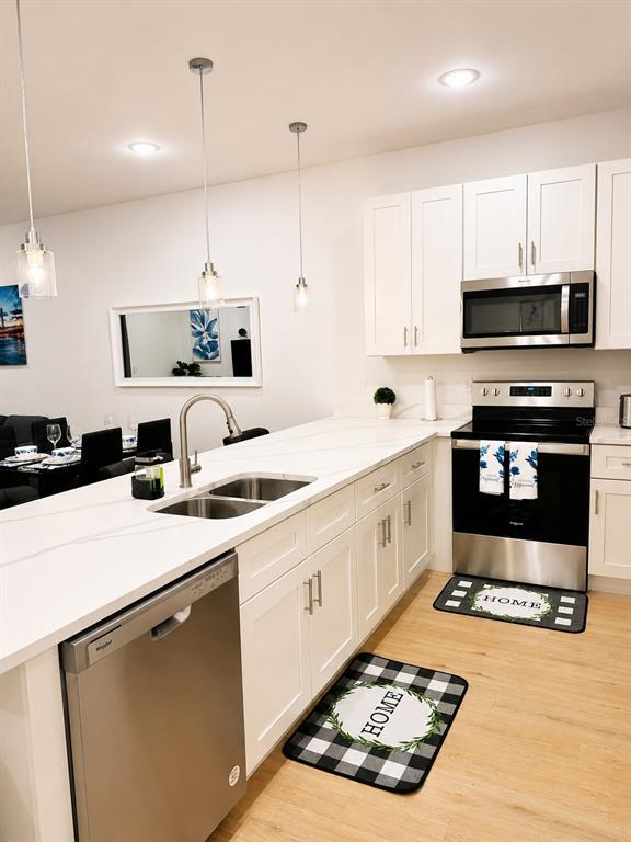 A modern kitchen features white cabinets, stainless steel appliances, a quartz island, and wood flooring — 289 BOUNDARY BOULEVARD UNIT 204, ROTONDA WEST, FL