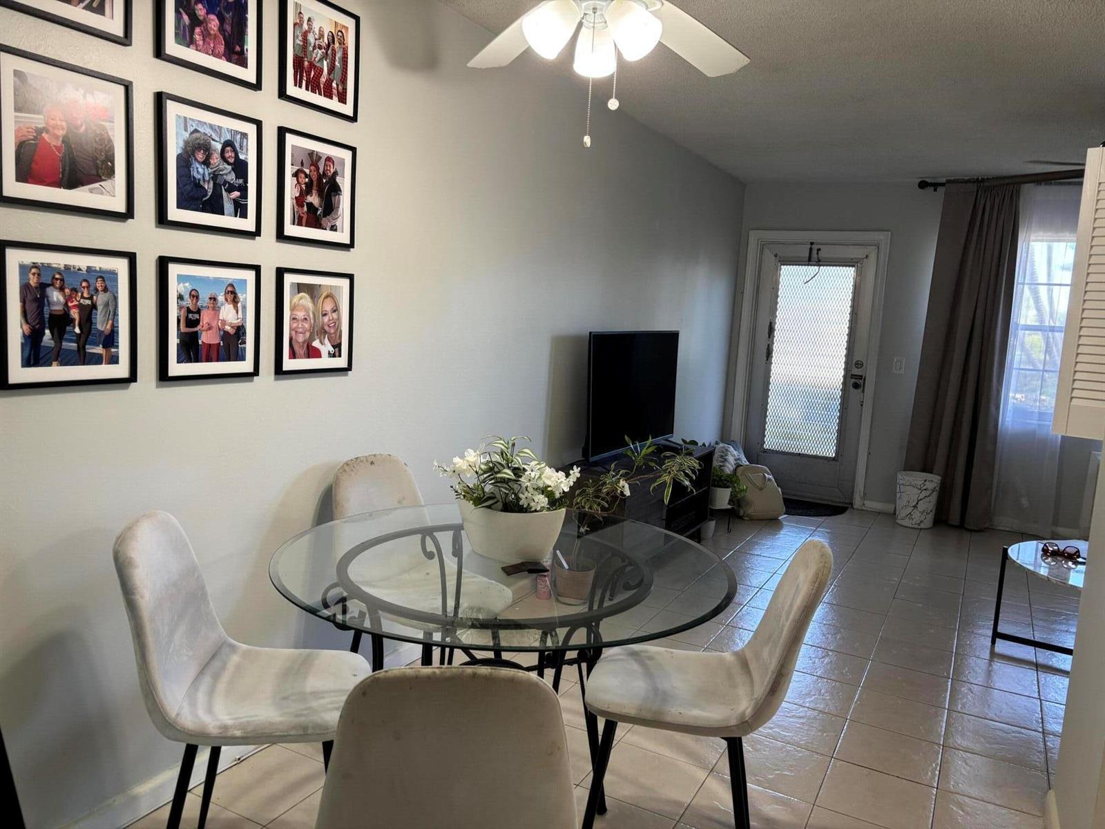 A dining area features a glass table, four upholstered chairs, and a gallery wall of photos — 243 Northampton M, West Palm Beach FL 33417, WEST PALM BEACH, FL