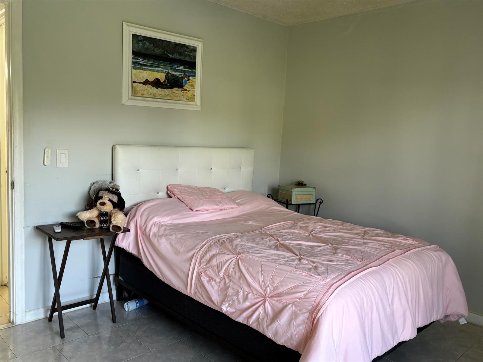 A bedroom features a white tufted headboard, a pink quilted bedspread, and a framed wall painting — 243 Northampton M, West Palm Beach FL 33417, WEST PALM BEACH, FL