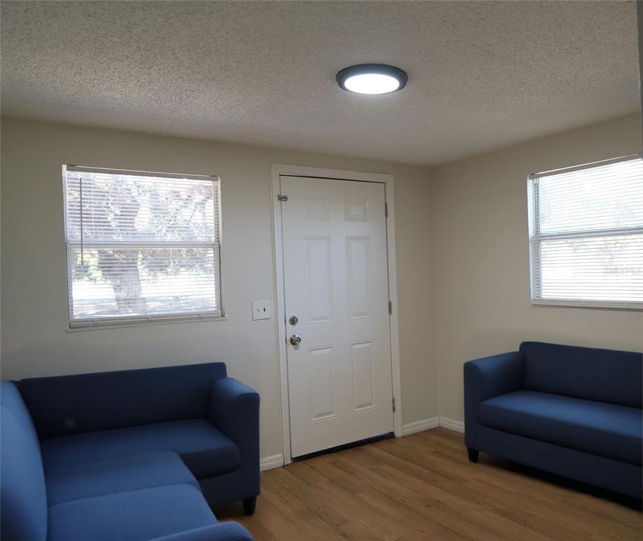 A room with light walls, wood-look flooring, two blue sofas, and a white entry door — 4509 N 29TH STREET, TAMPA, FL