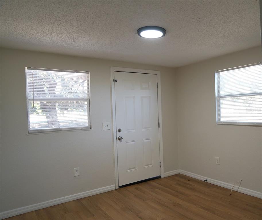 An interior room features light-colored walls, wood-look flooring, a white door, and two windows — 4509 N 29TH STREET, TAMPA, FL