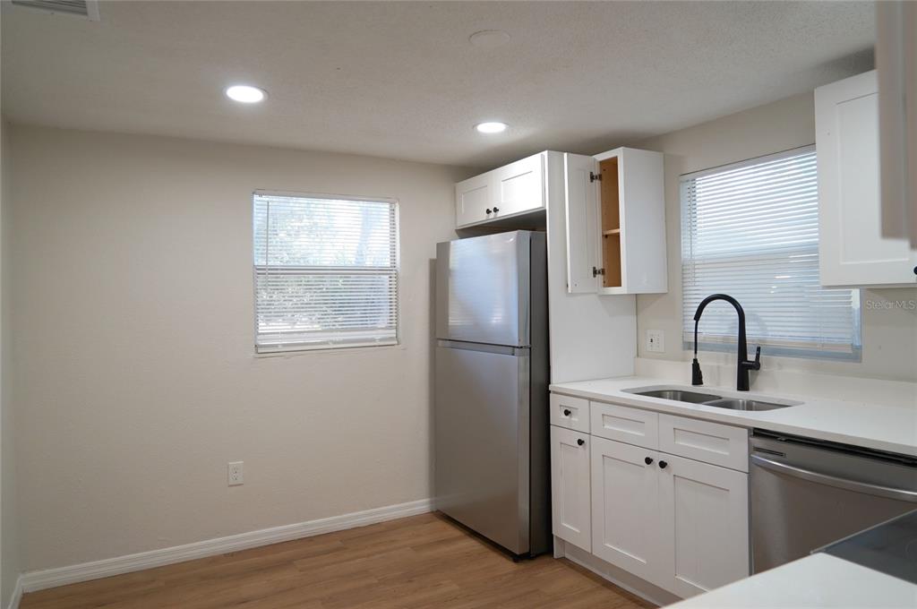 A kitchen features white cabinets, stainless steel appliances, a double sink, and light wood flooring — 4509 N 29TH STREET, TAMPA, FL
