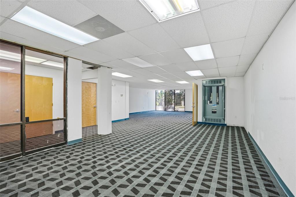 An empty office space features a patterned carpet, drop ceiling, and an exposed electrical panel — 5341 GRAND BOULEVARD UNIT 103, NEW PORT RICHEY, FL