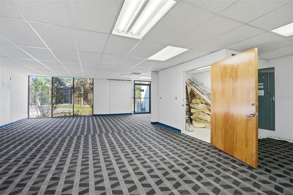 An empty office space features patterned carpet, a drop ceiling, and a storage closet — 5341 GRAND BOULEVARD UNIT 103, NEW PORT RICHEY, FL