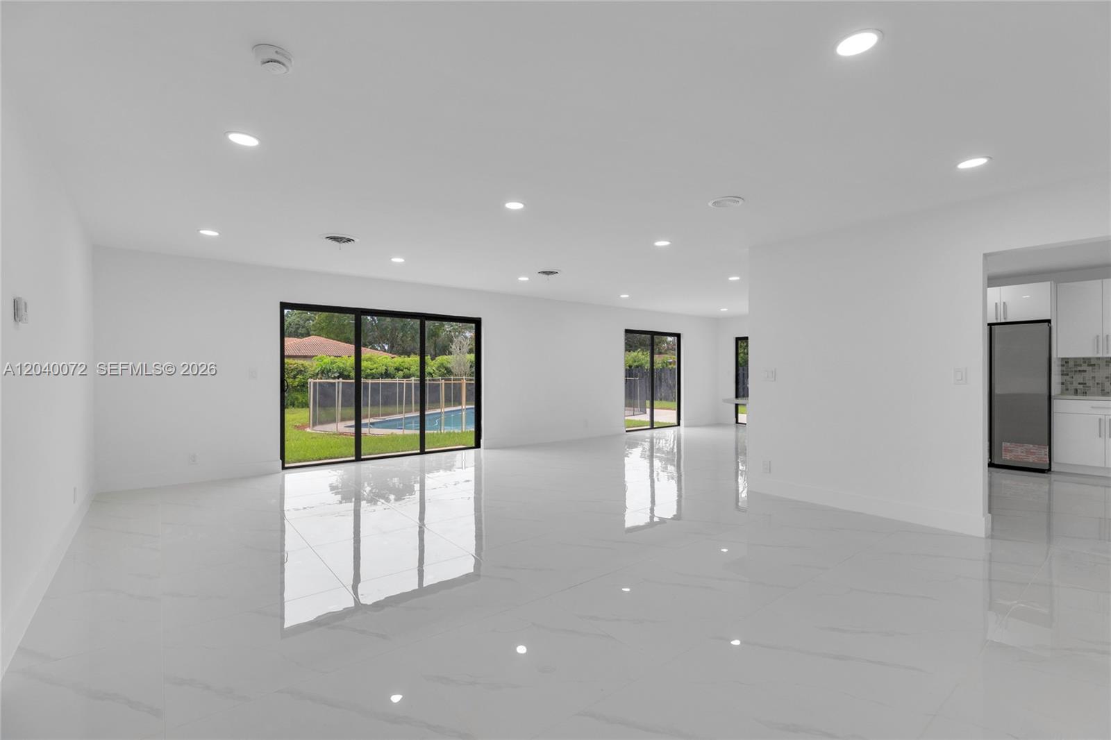 A bright, open-concept living area features white tile floors, recessed lighting, and sliding glass doors — 6940 NW 6th St, Plantation FL 33317, PLANTATION, FL